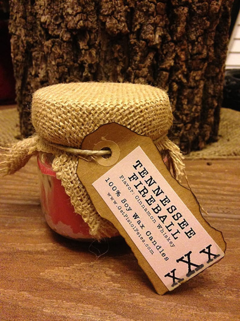 May include: A brown burlap-wrapped candle jar with a label that reads "Tennessee Fireball" and "Flavor: Cinnamon Whiskey 100% Soy Wax Candles www.GetPistolPets.com".