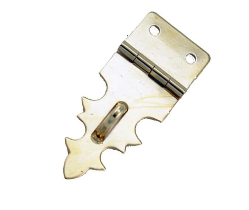 May include: A silver-toned metal hinge with a decorative, pointed, serrated edge. The hinge is closed and has a small, rectangular hole in the center.