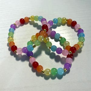 May include: Three beaded bracelets in a rainbow of colors. Each bracelet features small, round beads in shades of red, orange, yellow, green, blue, purple, and pink. The beads are strung together with gold-colored spacers.