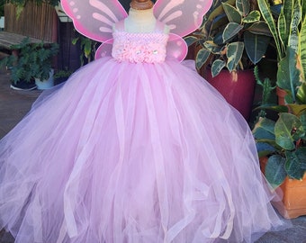 May include: A pink tulle tutu dress with a pink butterfly wing costume. The dress has a pink flower embellishment around the waist.