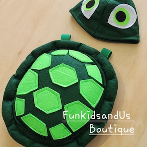 May include: Green felt turtle costume with a shell and a hat. The shell has a green felt design with a green felt border. The hat has two white felt eyes with green felt pupils.