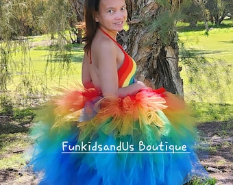 May include: A rainbow tulle tutu skirt with a crocheted rainbow halter top. The skirt is layered with tulle in shades of red, orange, yellow, green, blue, and purple. The text "FunkidsandUs Boutique" is visible on the skirt.