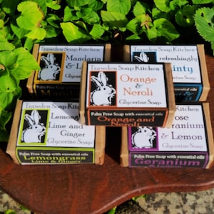 May include: Six bars of handmade soap with essential oils. The soaps are wrapped in brown paper with white bunny illustrations and black text. The scents are: Mandarin & Lime, Lemongrass Lime & Ginger, Orange & Neroli, Orange & Neroli, Rose Geranium & Lemon, and Geranium.