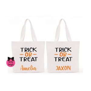 May include: Two white canvas tote bags with black and orange text. The text on the bags reads "Trick or Treat" with a name below. The first bag says "Amelia" and the second bag says "Jaxon".
