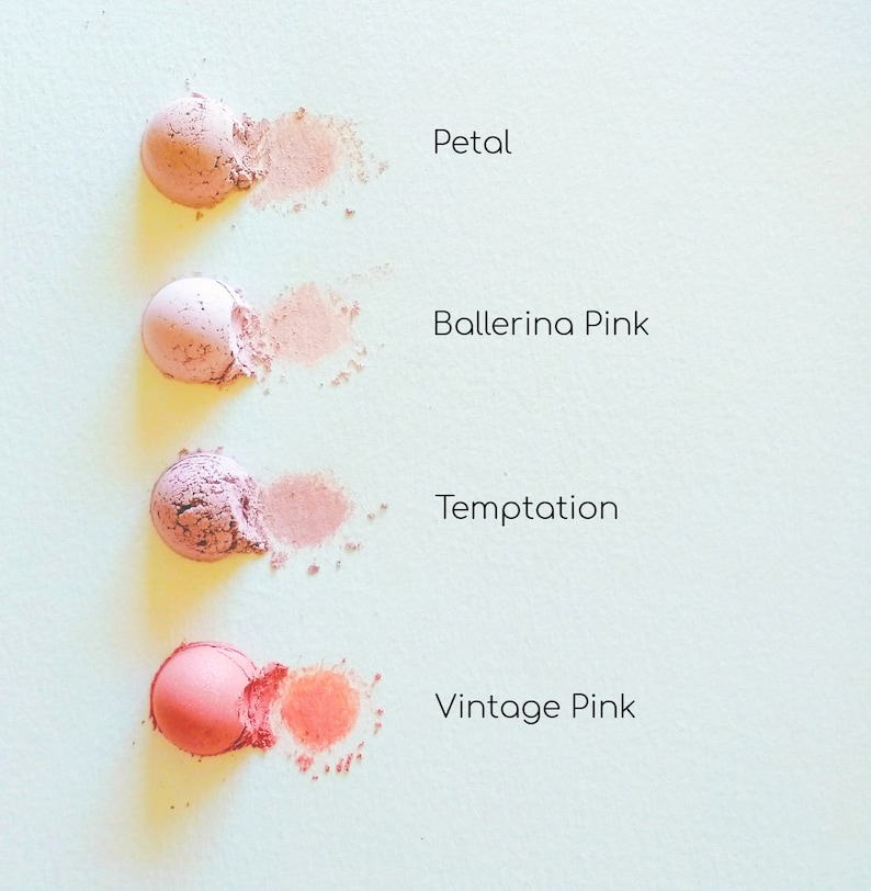 May include: Four different shades of blush makeup, from light pink to coral, are shown in small round containers. The shades are labelled "Petal", "Ballerina Pink", "Temptation", and "Vintage Pink".