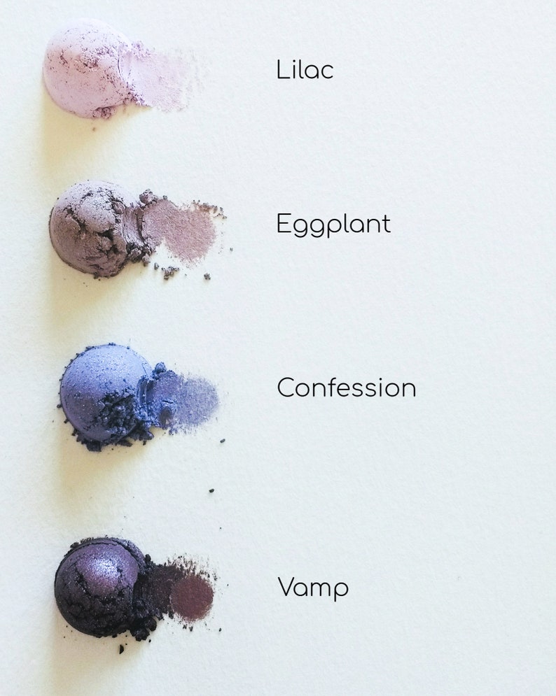 May include: Four eyeshadow samples in shades of purple, blue, and black. The shades are labelled "Lilac", "Eggplant", "Confession", and "Vamp".