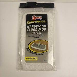 May include: A white hardwood floor mop refill in a clear plastic package. The label reads "Quickie PROFESSIONAL HARDWOOD FLOOR MOP REFILL" and includes the text "Cleans Hardwood & Tile Floors".
