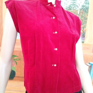 May include: A red corduroy button-up top with short sleeves and a mandarin collar.