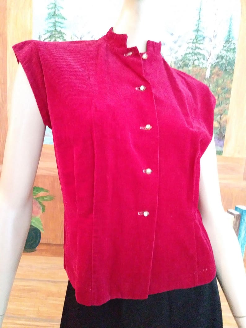 May include: A red corduroy button-up top with short sleeves and a mandarin collar.