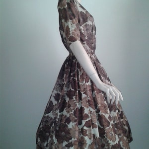 May include: A brown and white floral print dress with a fitted bodice and a full skirt. The dress has a short sleeve and a v-neck.