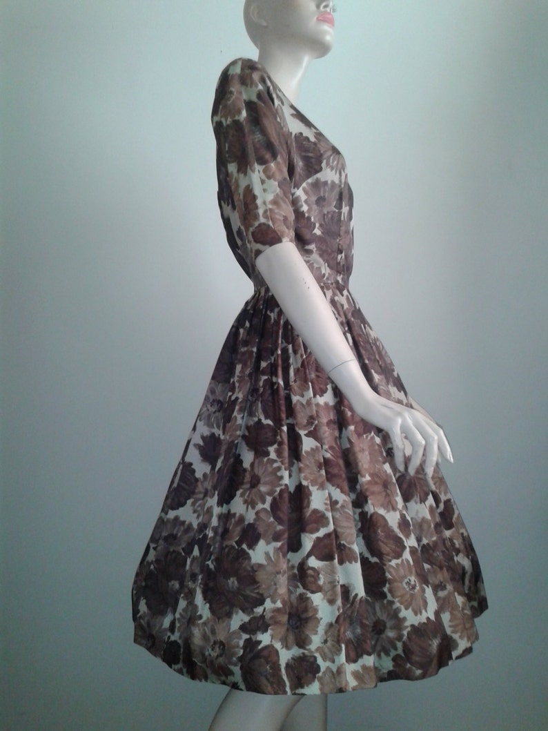 May include: A brown and white floral print dress with a fitted bodice and a full skirt. The dress has a short sleeve and a v-neck.
