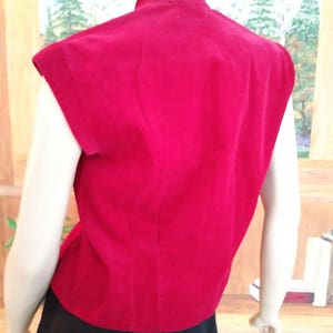 May include: A sleeveless red velvet top with a high neckline and a fitted silhouette.