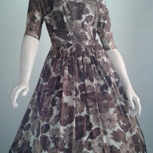May include: A vintage floral dress with a brown and white floral print. The dress has a fitted bodice and a full skirt.
