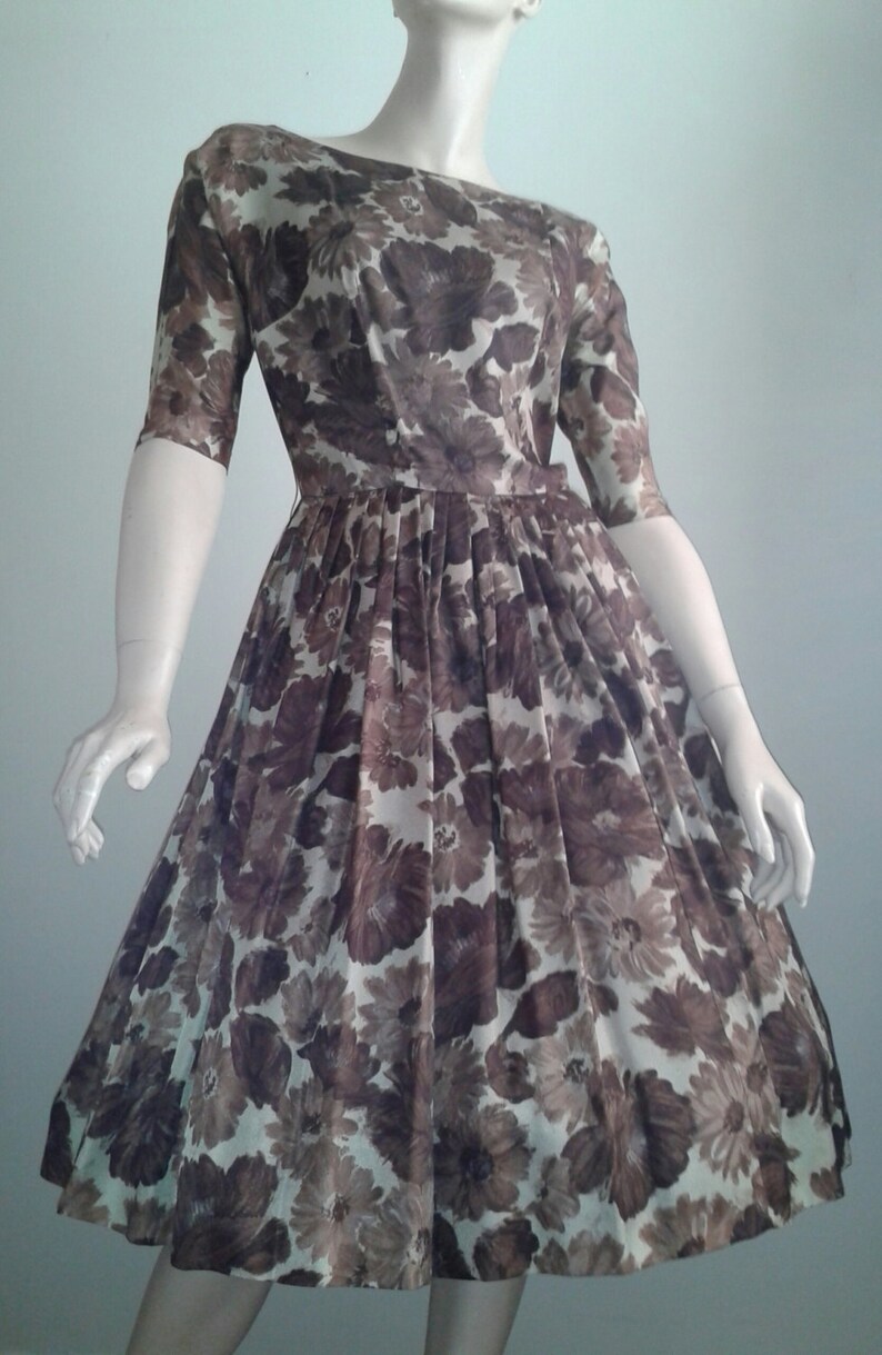 May include: A vintage floral dress with a brown and white floral print. The dress has a fitted bodice and a full skirt.