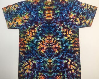 May include: A tie-dye t-shirt with a vibrant, symmetrical pattern. The shirt features a blend of colors, including blue, orange, yellow, and purple. The design is intricate and abstract, creating a unique visual effect. The shirt is a classic crew neck style.