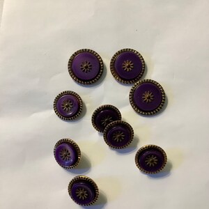 May include: Nine purple buttons with a gold rim and a flower design in the center.
