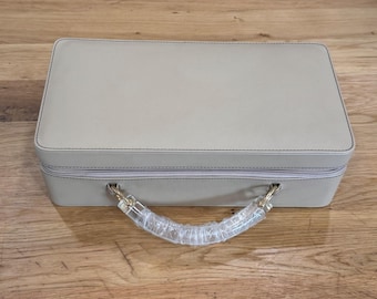 Neceser de piel sintética beige de Estée Lauder con asa de acrílico y tono dorado