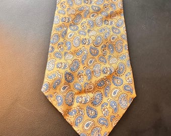 May include: A yellow paisley tie with a repeating pattern of blue and white teardrop-shaped designs. The tie is made of a smooth fabric and is displayed on a dark surface. The tie is a classic accessory.