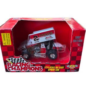 May include: A 1/24 scale die-cast sprint car model in a red and black box. The car is white and red with the number 2 and "Pioneer Concrete" printed on it. The box reads "Racing Champions" and "1997 Edition".