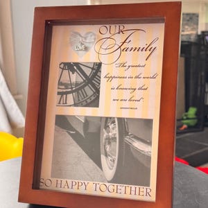 Peut inclure: Un cadre photo en bois marron avec les mots "OUR Family" et "SO HAPPY TOGETHER". Le cadre contient une image d'horloge, une image de roue de voiture et une citation sur l'amour. Le cadre a un cœur avec le mot "LOVE".