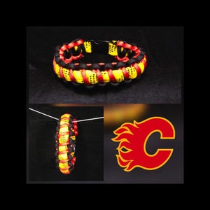 May include: A paracord bracelet woven with black, red, and yellow cord featuring a black plastic side-release buckle. The design includes a graphic of a red letter C with yellow flames, consistent with the Calgary Flames sports team logo.