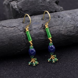 May include: A pair of gold dangle earrings with green and blue gemstone beads. The earrings feature a long green bead, a round blue bead, and smaller green beads.