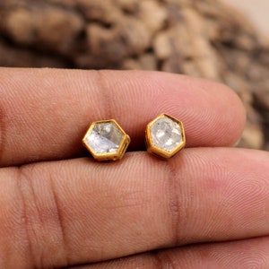 May include: A pair of gold stud earrings with hexagonal clear gemstones.