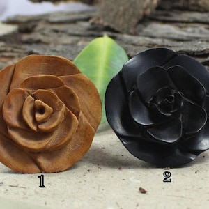 May include: Two wooden rose carvings, one in natural wood and one in black. The carvings are detailed and realistic.