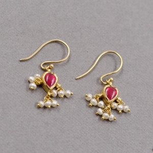 May include: A pair of gold earrings with a red gemstone and white pearl accents.