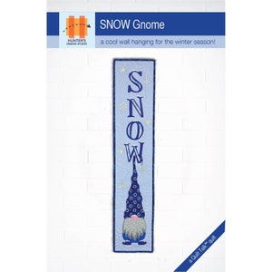 May include: A blue and white quilted wall hanging featuring a gnome with a blue hat and a white beard. The gnome is standing on a blue background with white snowflakes. The word "SNOW" is spelled out in blue letters on the hanging.