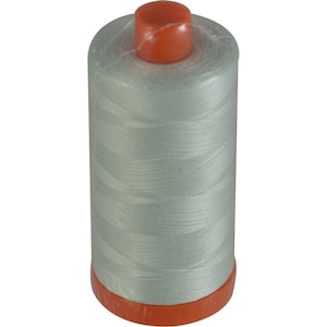 May include: A spool of light blue thread with an orange plastic top.