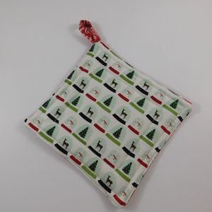 May include: White quilted pot holder with a red and green trim. The pot holder has a loop handle and features a repeating pattern of snow globes with deer inside.
