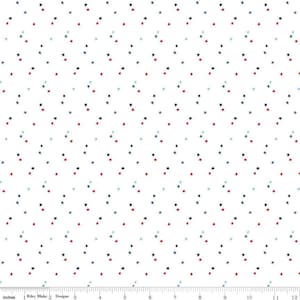 May include: White fabric featuring a repeating pattern of small stars in red, navy blue, and light blue. The stars are scattered across the surface. The bottom of the image shows a ruler with inches.