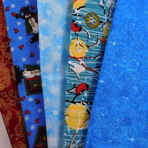 Peut inclure: Cinq échantillons de tissu sur le thème des fêtes d'hiver. Les échantillons sont bleus, turquoise et rouges avec des flocons de neige blancs, des bonhommes de neige, des oiseaux et des branches.