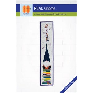 May include: A quilted wall hanging featuring a gnome sitting on a stack of books. The gnome is wearing a blue hat and orange trousers. The word "READ" is spelled out in purple letters above the gnome. The hanging is titled "READ Gnome" and is described as "a cool wall hanging for educators!"