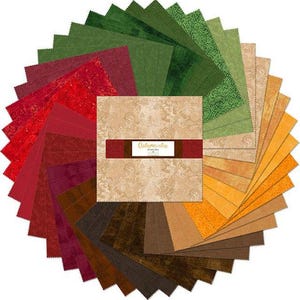 May include: A circular arrangement of fabric squares in shades of green, red, brown, and gold. The center features a square with the text "Autumnatic" on a brown band. The fabrics have various textures and patterns, suitable for quilting or crafting projects.