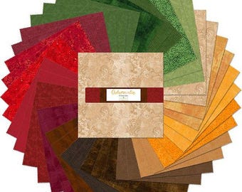 May include: A circular arrangement of fabric squares in shades of green, red, brown, and gold. The center features a square with the text "Autumnatic" on a brown band. The fabrics have various textures and patterns, suitable for quilting or crafting projects.