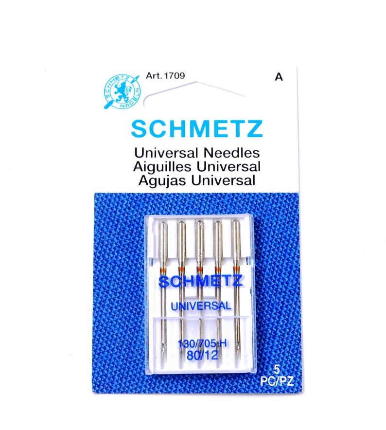 May include: A package of 5 Schmetz Universal sewing machine needles in a clear plastic case. The needles are silver and have a red band near the top. The package is blue and white and has the text "Art. 1709", "SCHMETZ", "Universal Needles", "Aiguilles Universal", "Agujas Universal", "SCHMETZ", "UNIVERSAL", "130/705 H", "80/12", "5 PC/PZ".