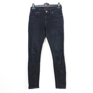 May include: Dark wash denim jeans hanging on a black hanger. The jeans have a classic five-pocket design, a button and zipper closure, and a slim fit. The jeans are a deep indigo color.
