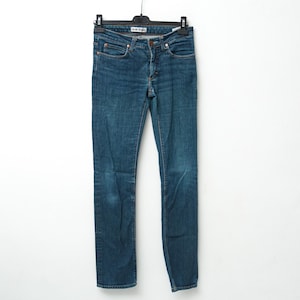 May include: Blue denim jeans hanging on a black hanger. The jeans have a classic five-pocket design, a button and zipper closure, and copper-colored rivets. The jeans are a medium wash with some fading and wear.
