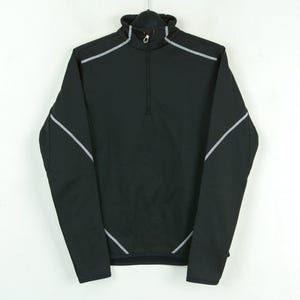 May include: Black athletic jacket with a mock neck and a quarter-zip. The jacket has reflective silver-grey accents on the shoulders and sleeves. It is hanging against a white background.