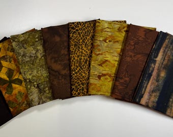 May include: A set of ten fabric squares in various shades of brown, yellow, and green. The fabric squares have different patterns, including stripes, dots, and swirls.