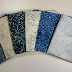 May include: Six fabric squares in shades of blue and white with various patterns. The fabric squares are arranged in a semi-circle.