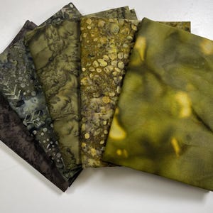 May include: A set of six fabric squares in shades of green and brown with a variety of patterns. The fabric squares are made of a soft, natural material and have a hand-dyed look.