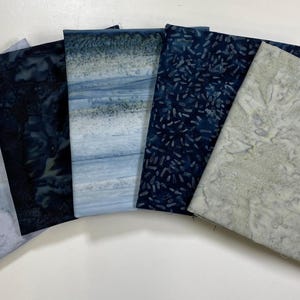 May include: Five fabric swatches in shades of blue and white. The swatches have different patterns, including a marbled design, a speckled design, a striped design, and a solid colour.