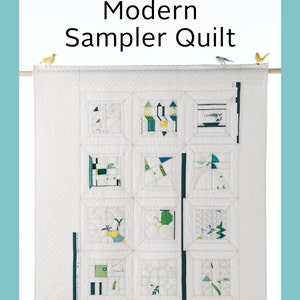 May include: A white quilt with a modern sampler design featuring geometric shapes in shades of green, black, and yellow. The quilt is hanging on a wall with two small yellow birds perched on the top edge.