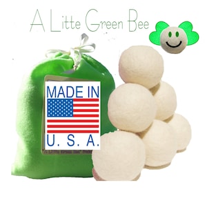 May include: A set of six white wool dryer balls in a green drawstring bag with a label that says "Made in U.S.A.".