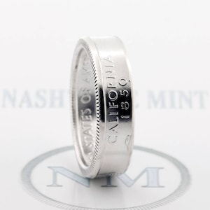 May include: A silver ring made from a United States half dollar coin. The coin is dated 1850 and reads "United States of America" and "California 1850".