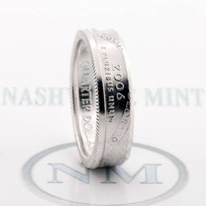 May include: A silver ring made from a 2006 Colorado quarter dollar coin. The ring features the inscription "E PLURIBUS UNUM" and "QUARTER DOLLAR" on the side.