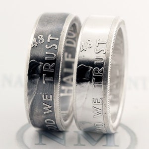May include: Two silver rings made from half dollar coins. The rings are engraved with the words "In God We Trust" and "48".